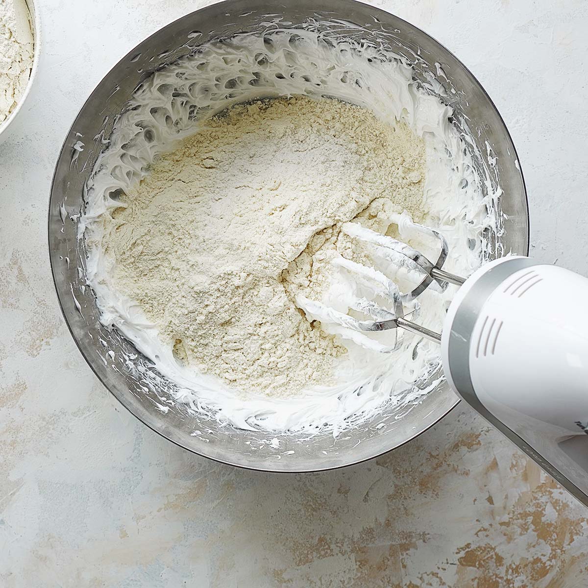 Kneading with a hand mixer flour and lard in a large mixing bowl.