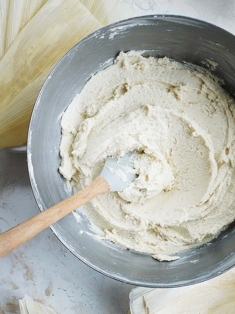 A large mixing bowl with a spatula and prepared masa dough.