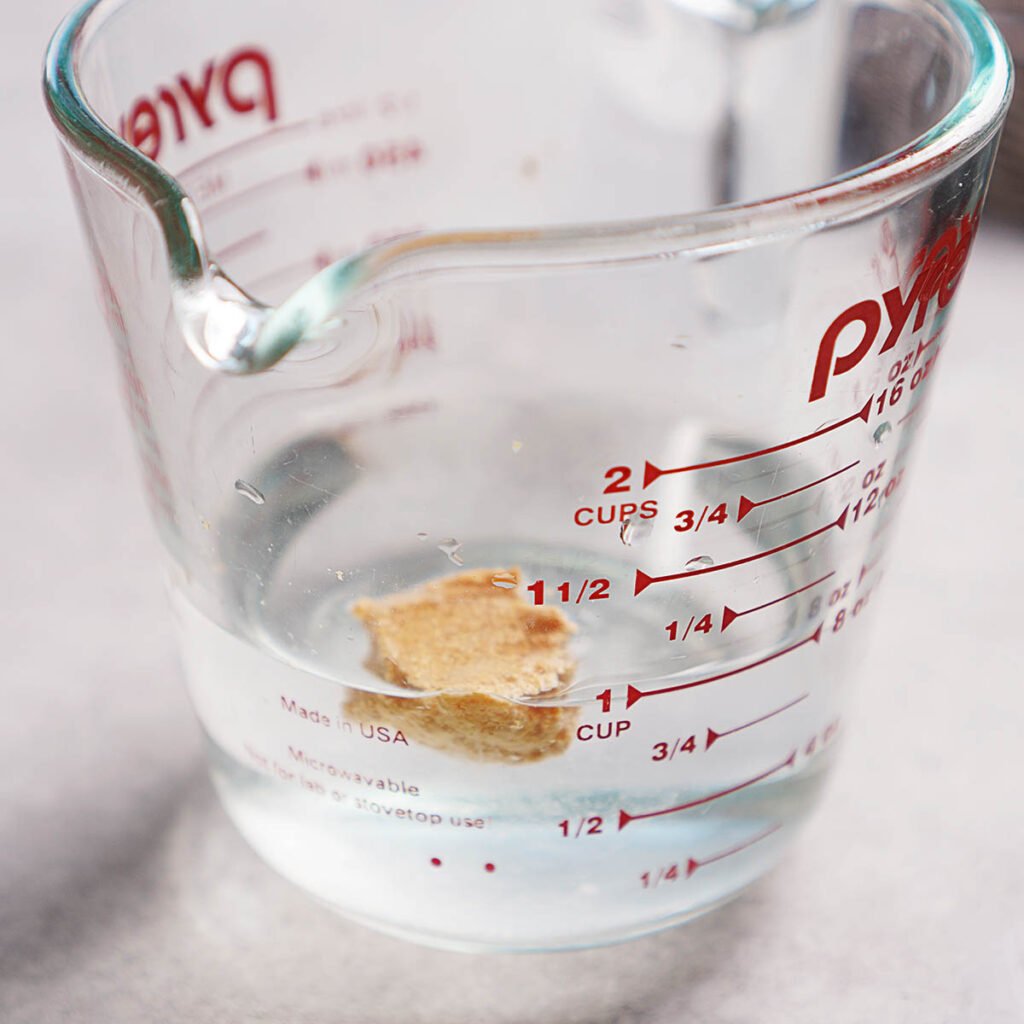 A mixing cup with water and a dollop of masa floating on top.