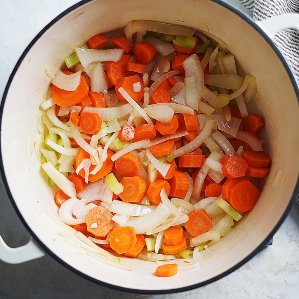 Sauteing carrots, celery, and onions in a large pot.
