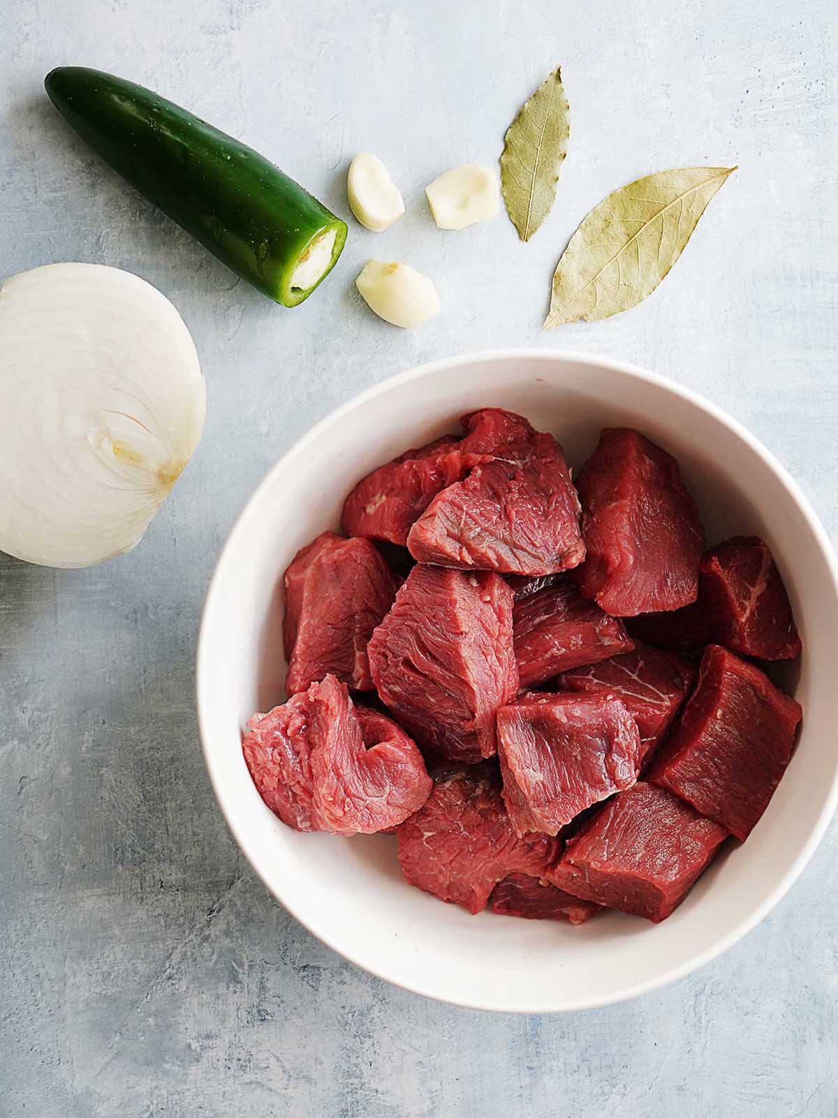 A bowl with raw chunks of beef.