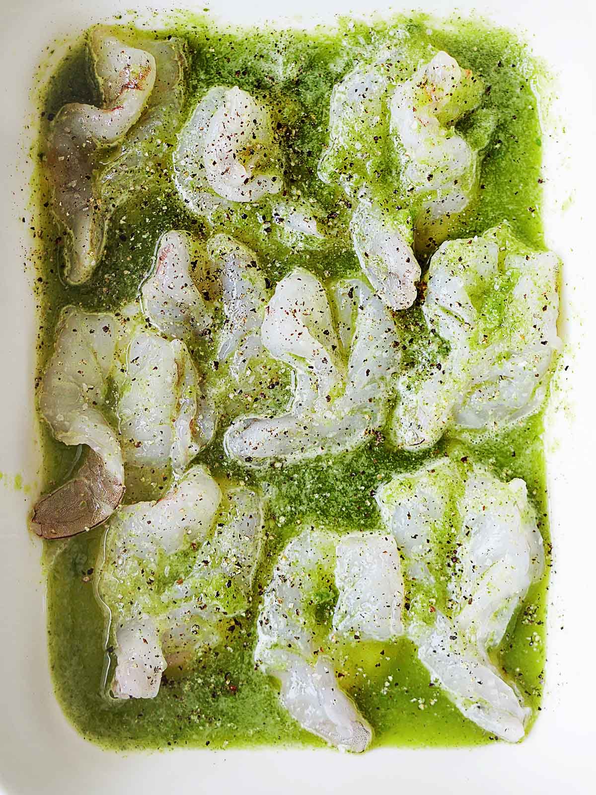 A serving dish with raw shrimp marinating in chile water.