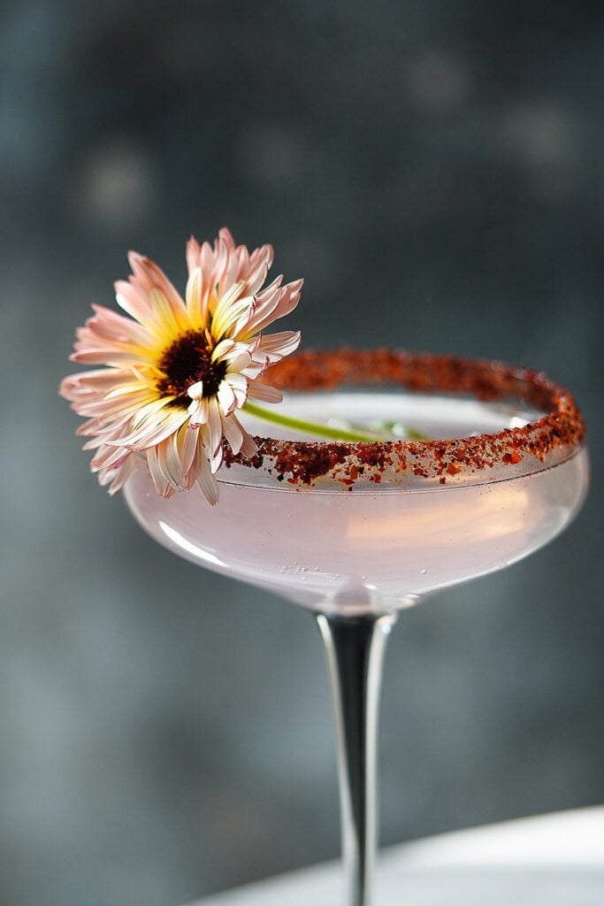 A cocktail glass garnished with a flower.