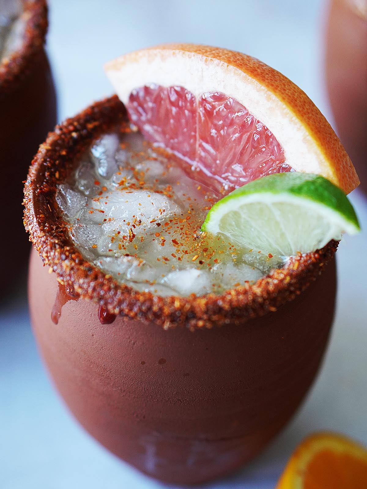 A cantarito cup with a cocktail garnished with a slice of grapefruit.
