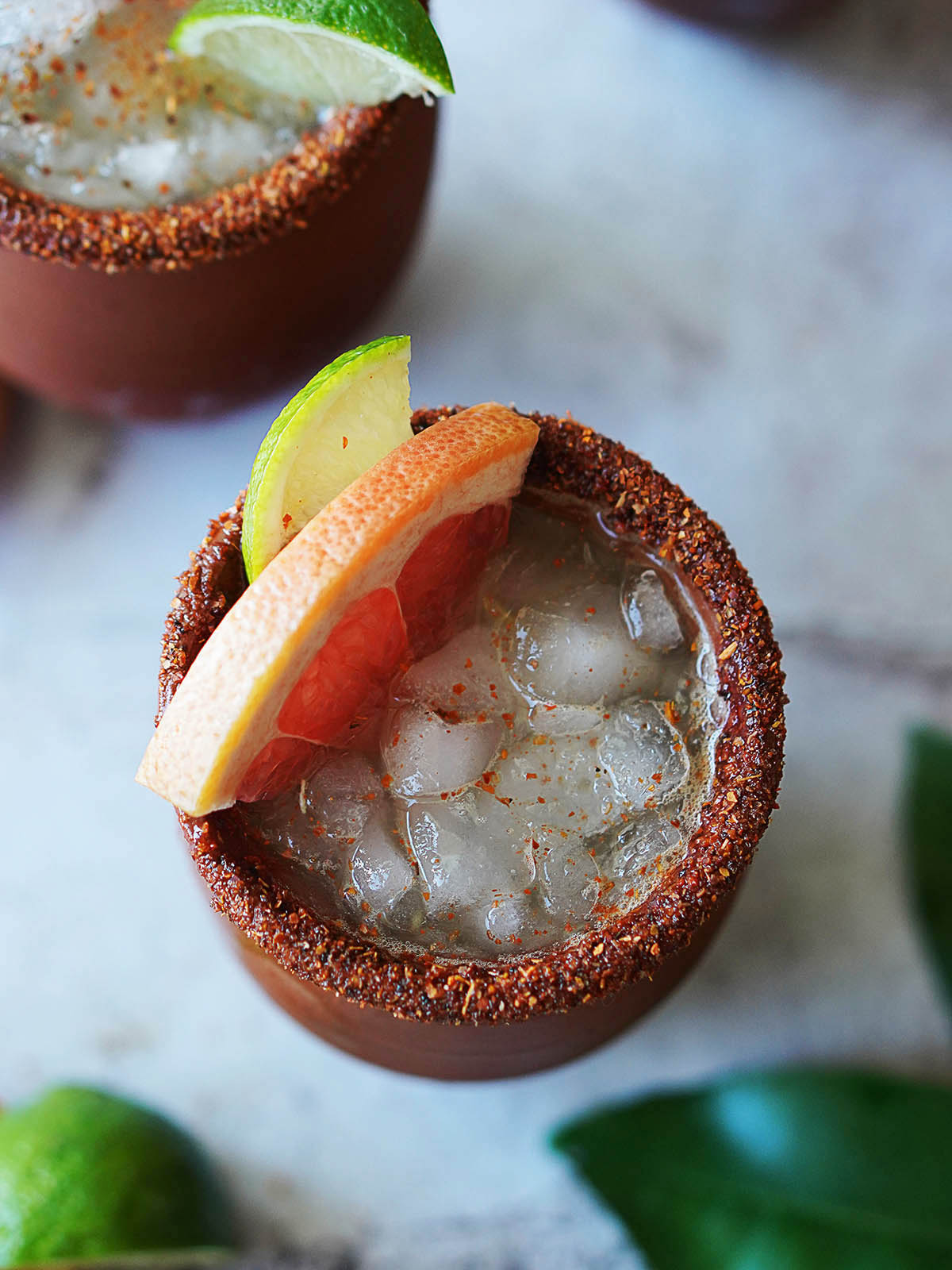 A Cantarito cup with a cocktail garnished with a slice of grapefruit.