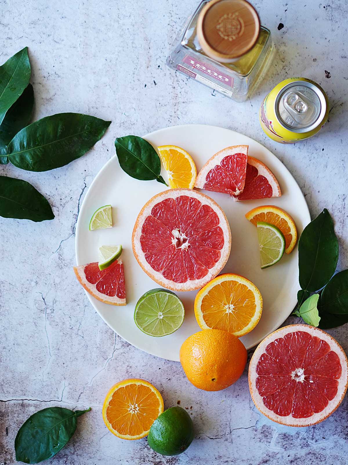 Oranges, grapefruits and lime cut into slices placed on a white plate.