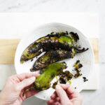 Peeling green peppers with two hands.