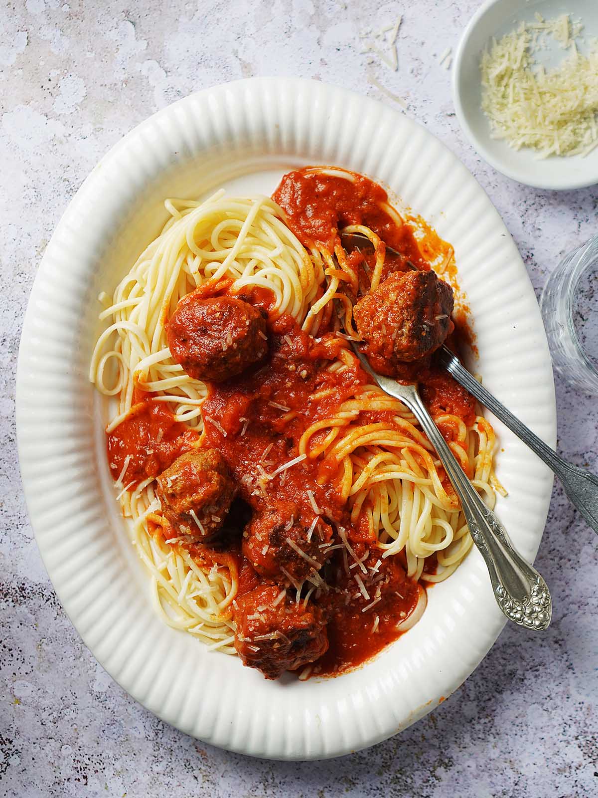 A large serving plate with healthy beef meatballs and cooked spaghetti.