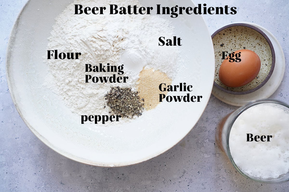 The dry ingredients for the batter in a bowl with a beer next to it.