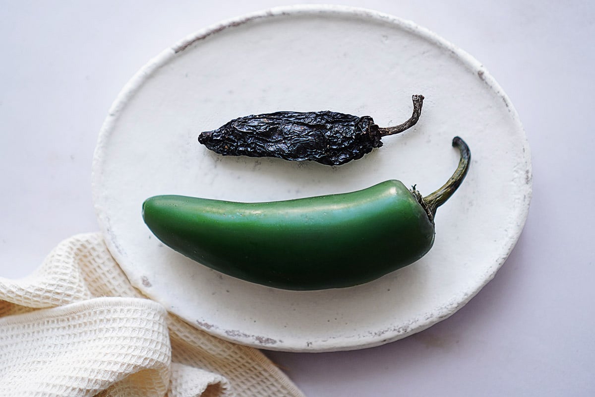 One chile morita and one chile jalapeño on a plate.