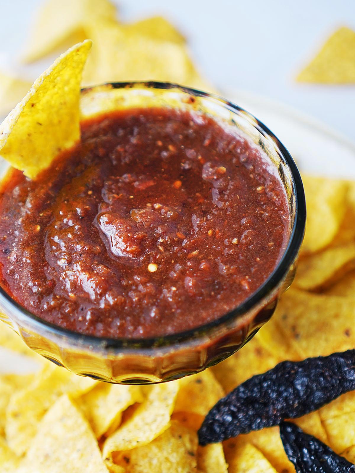 A bowl of salsa with tortilla chips on the side.