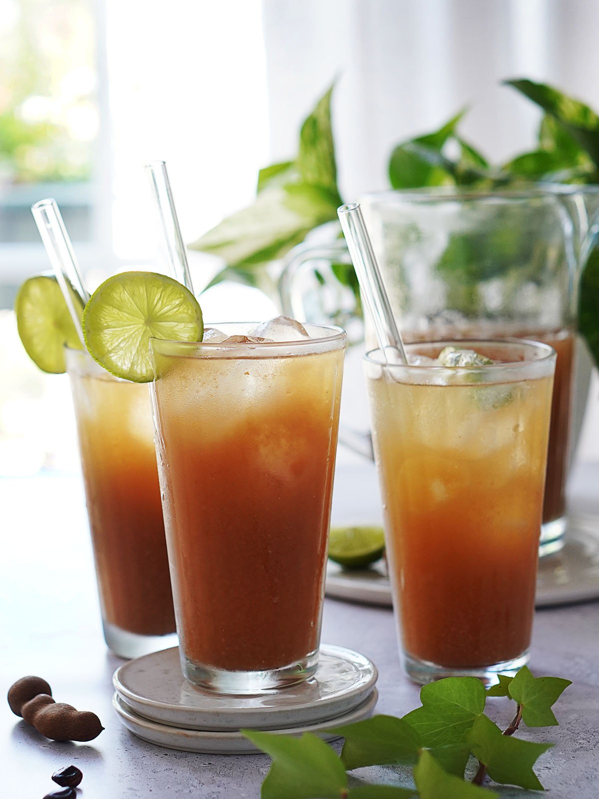 Three glasses with agua de tamarindo garnished a slice of lime.