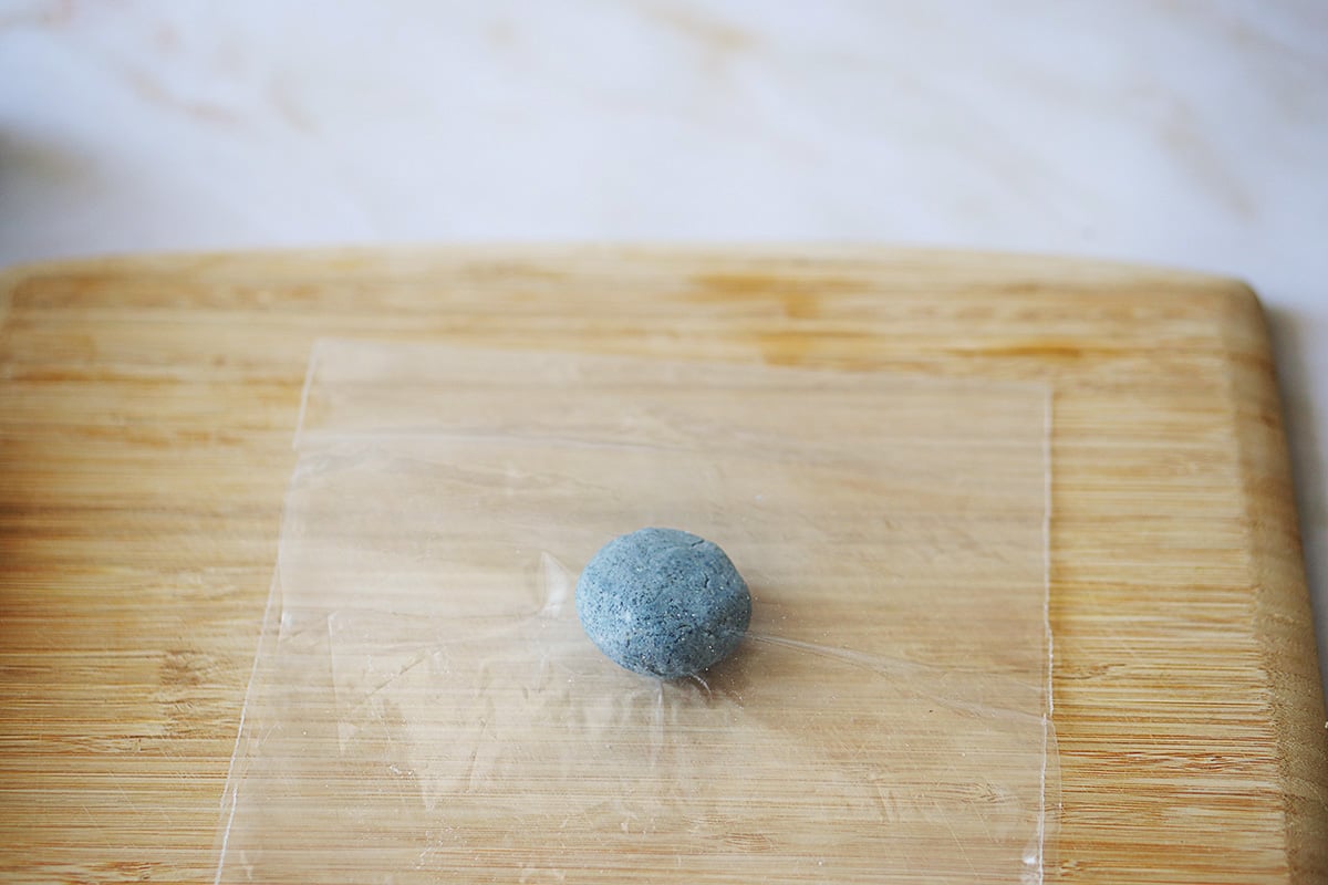 A masa ball in between two pieces of plastic.