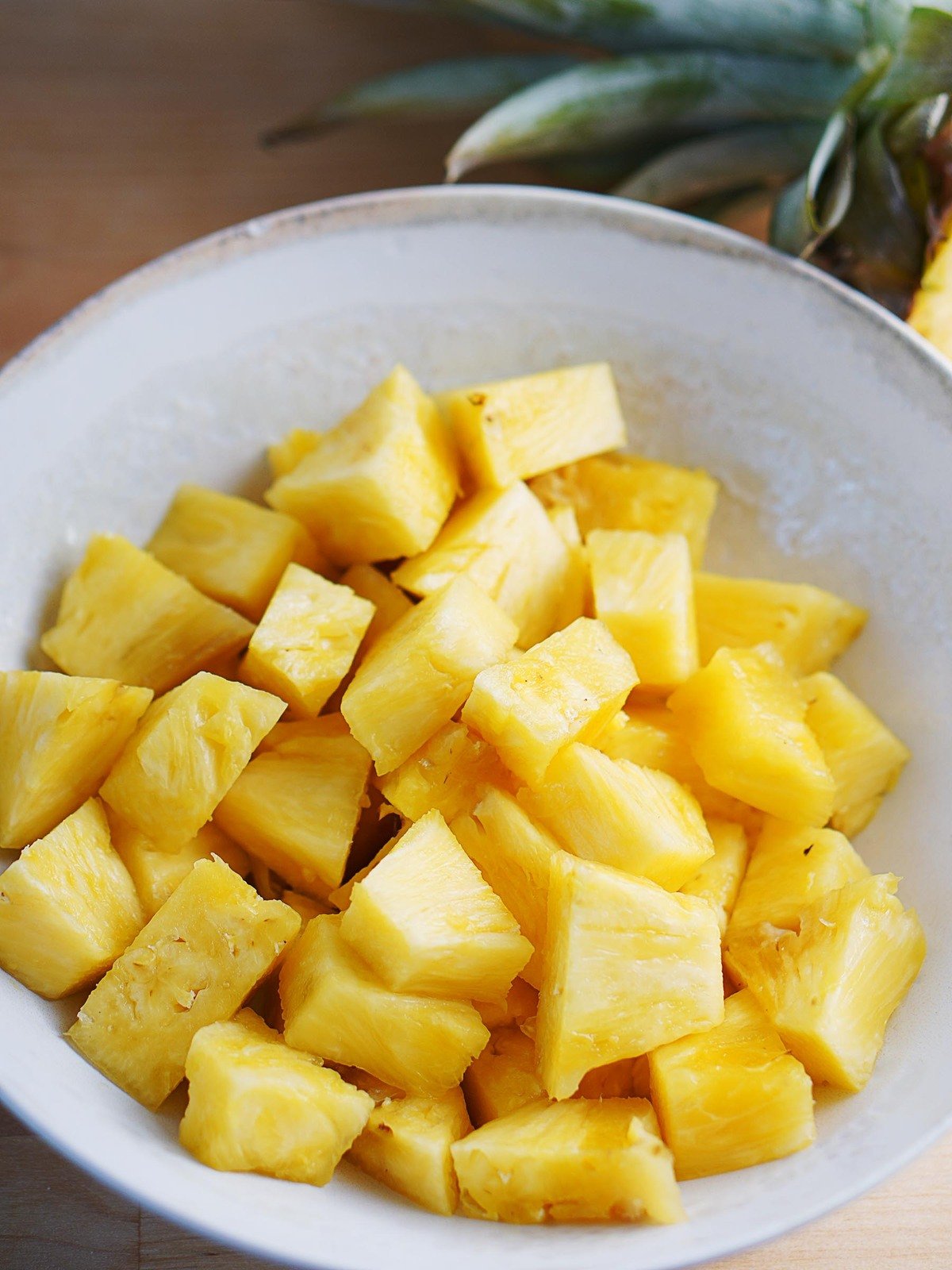 A white bowl of pineapple cubes.