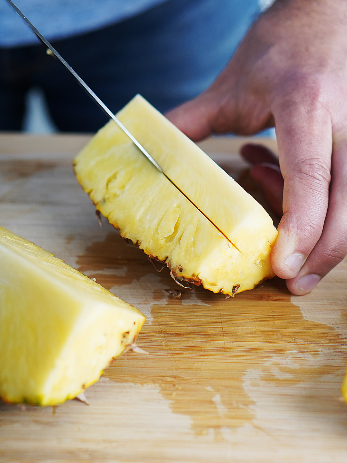 A person showing how to slice a pineapple.