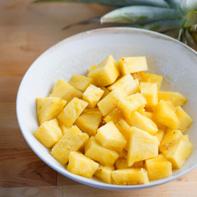 A white bowl with fresh pineapple cubes.