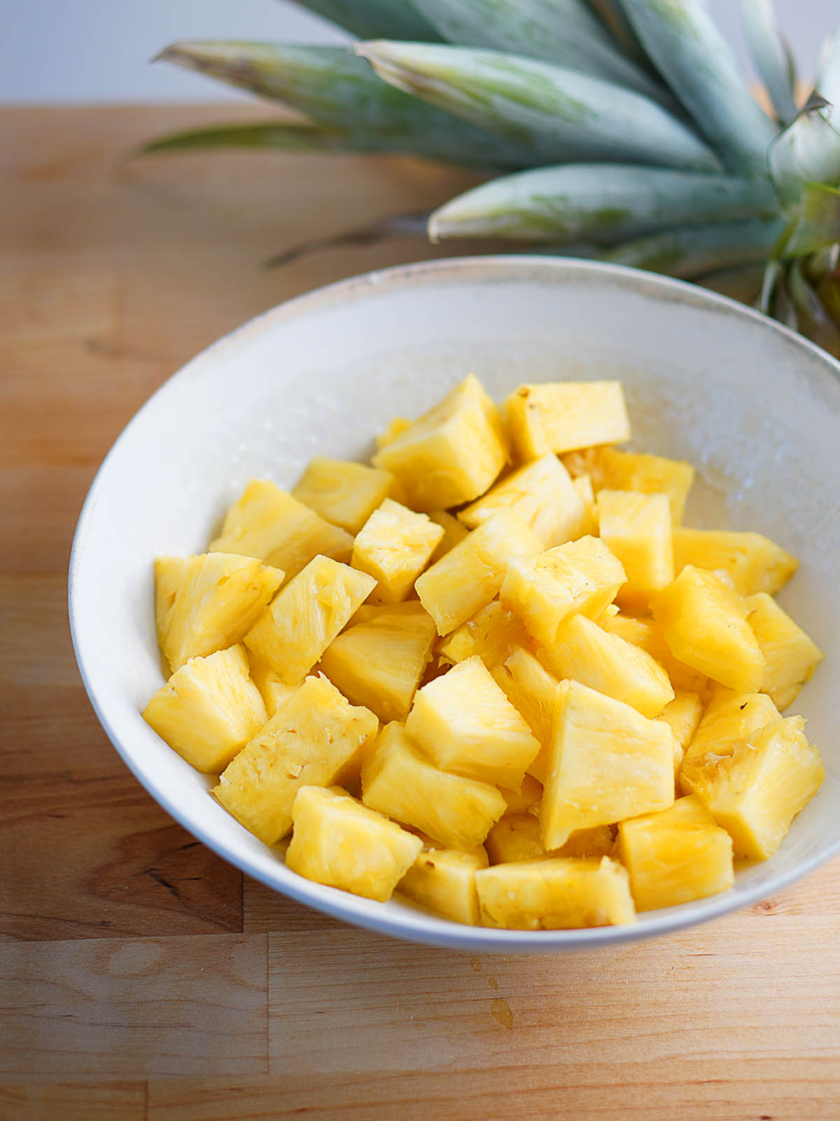 A white bowl with fresh pineapple cubes.