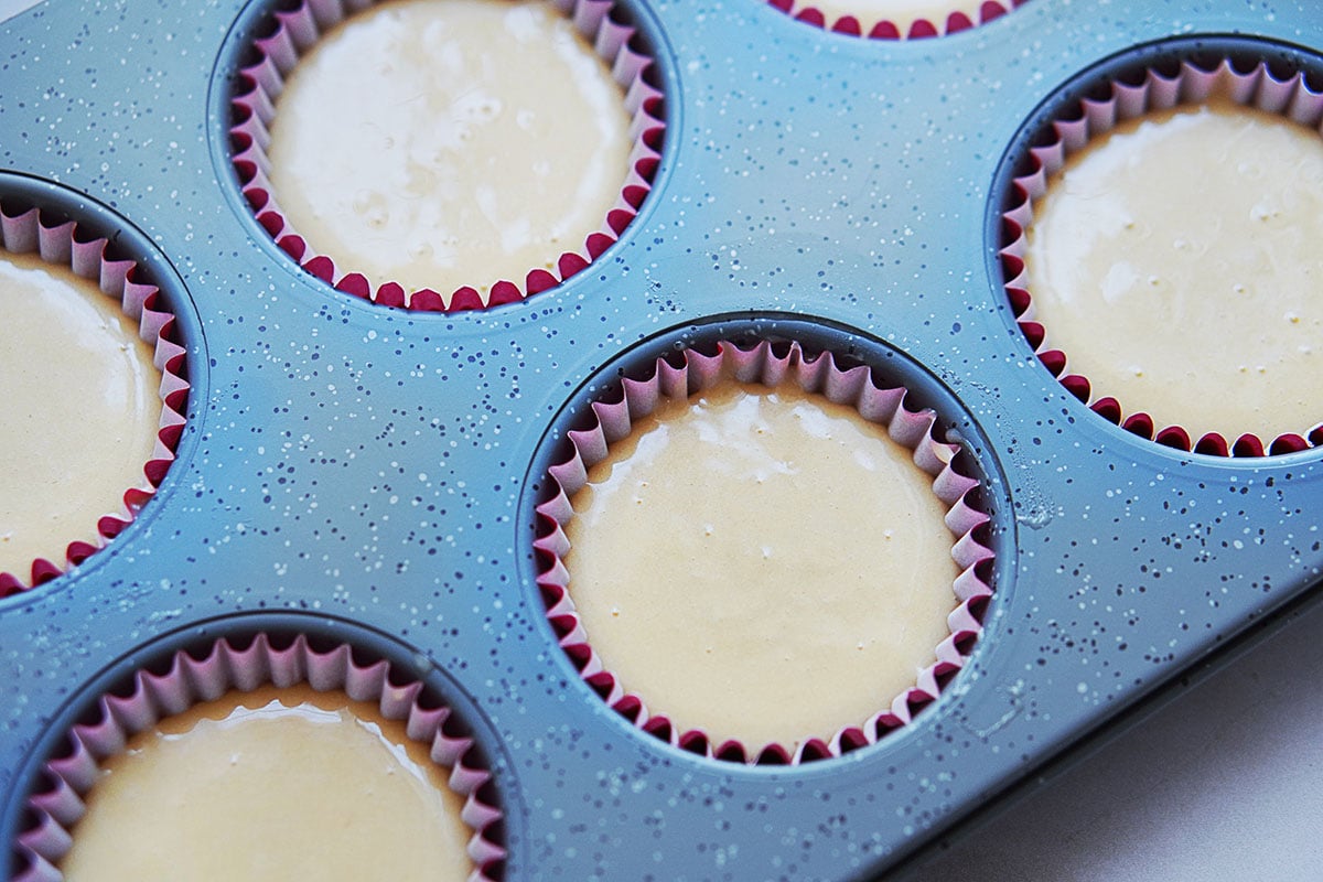 A muffin mold with cupcake lines and batter inside.