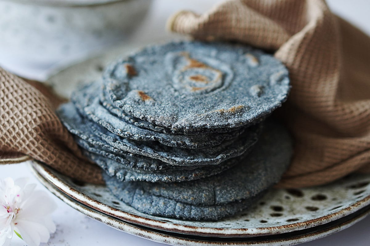 A stack of blue corn tortillas placed on a kitchen towel.