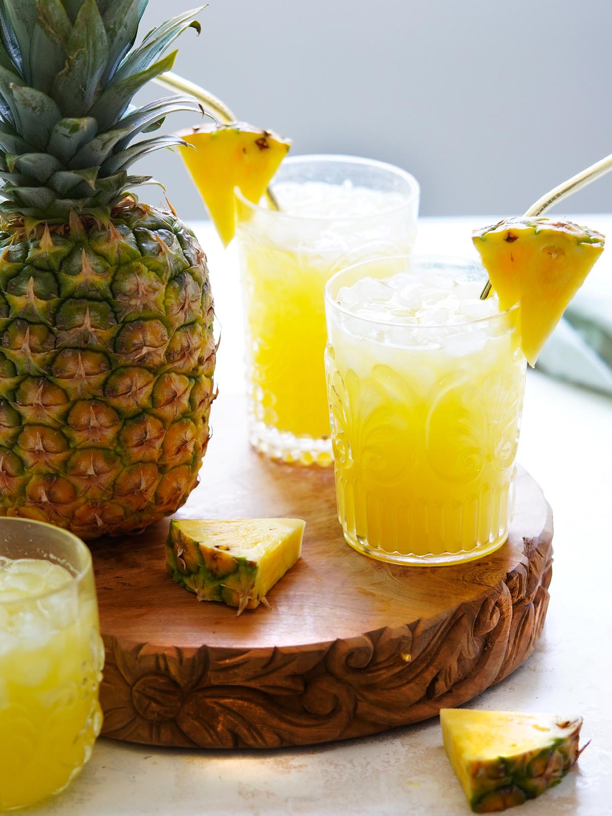 3 cups with pineapple water with a whole pineapple on the side.