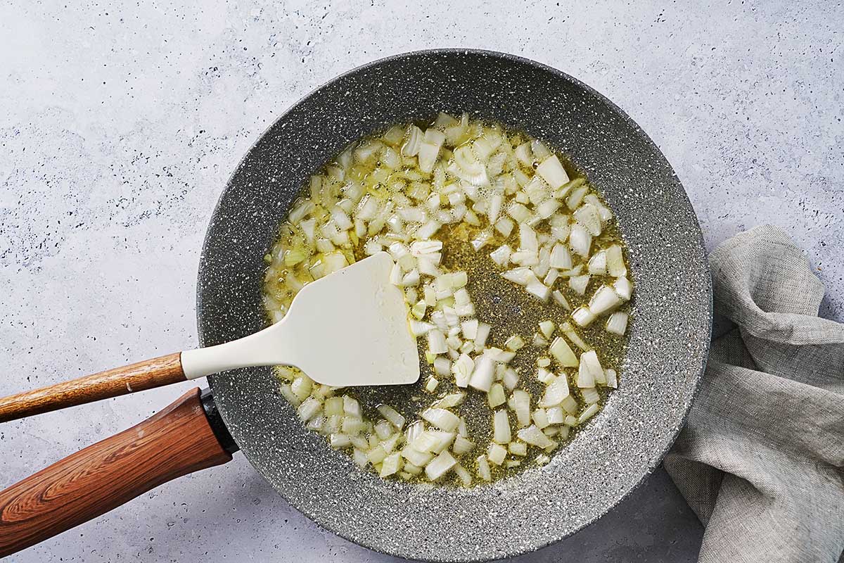 Cooking onions in butter in a gray skillet.