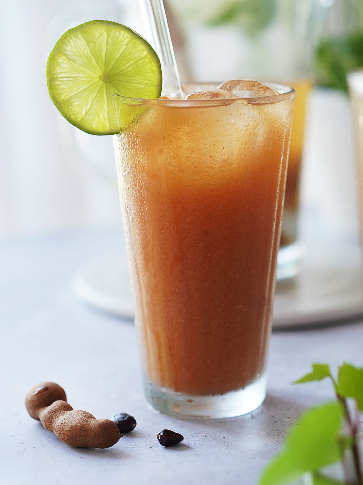A glass with tamarind water garnished with a lime slice.