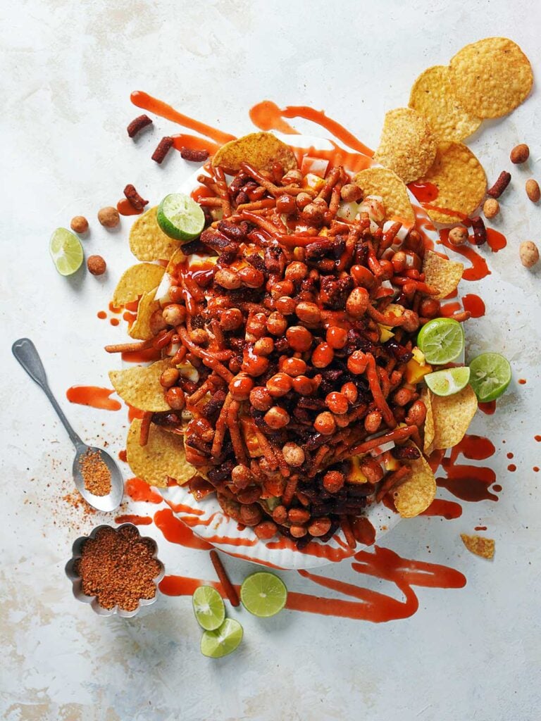 A plate with tostilocos drizzled with chamoy and lime juice.