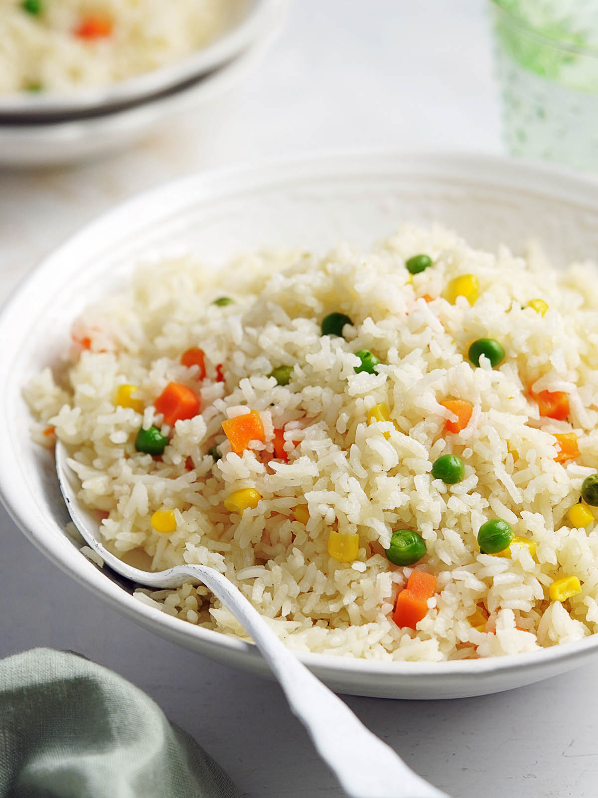 A white bowl with Arroz Primavera with a white spoon in it.