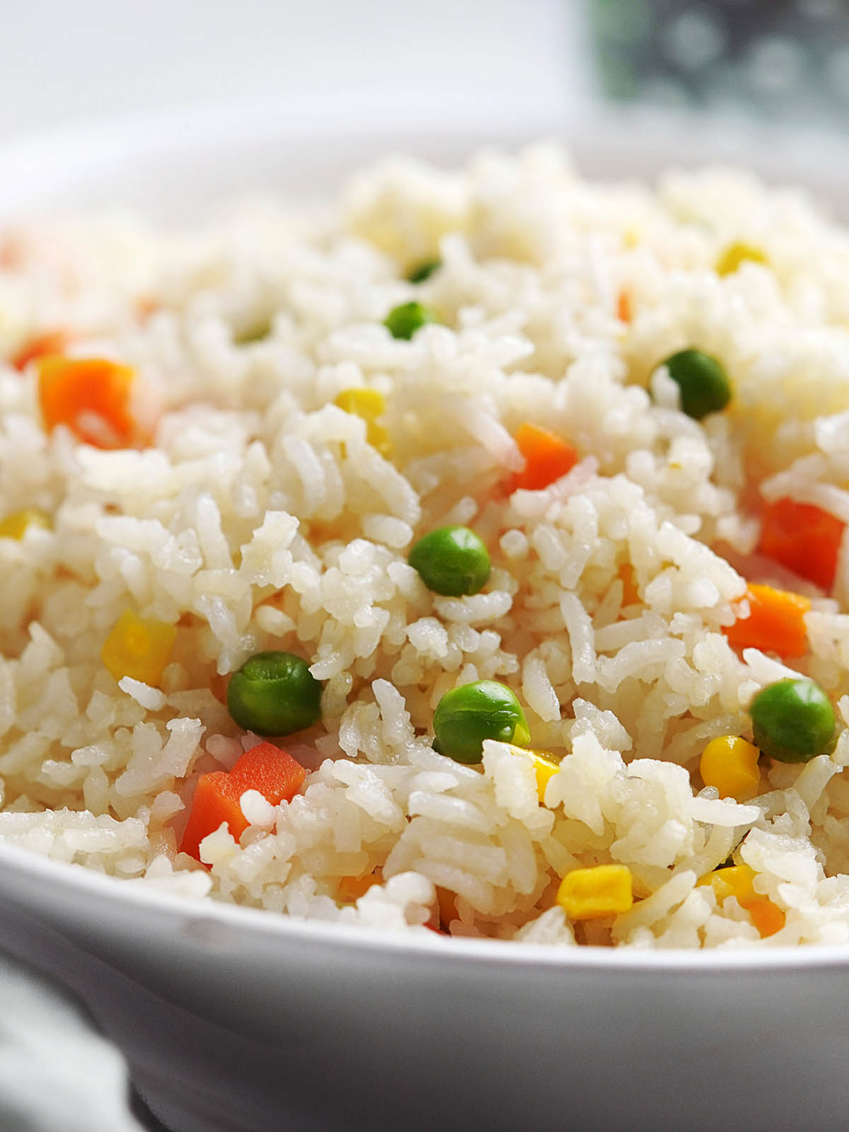 A white bowl with white rice and vegetables.