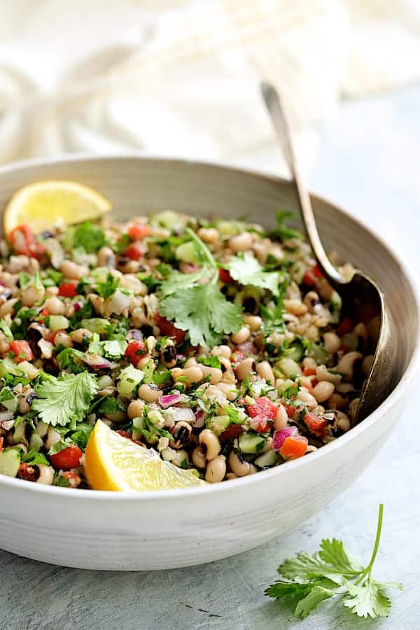 A white bowl with black eyed pea salad. 
