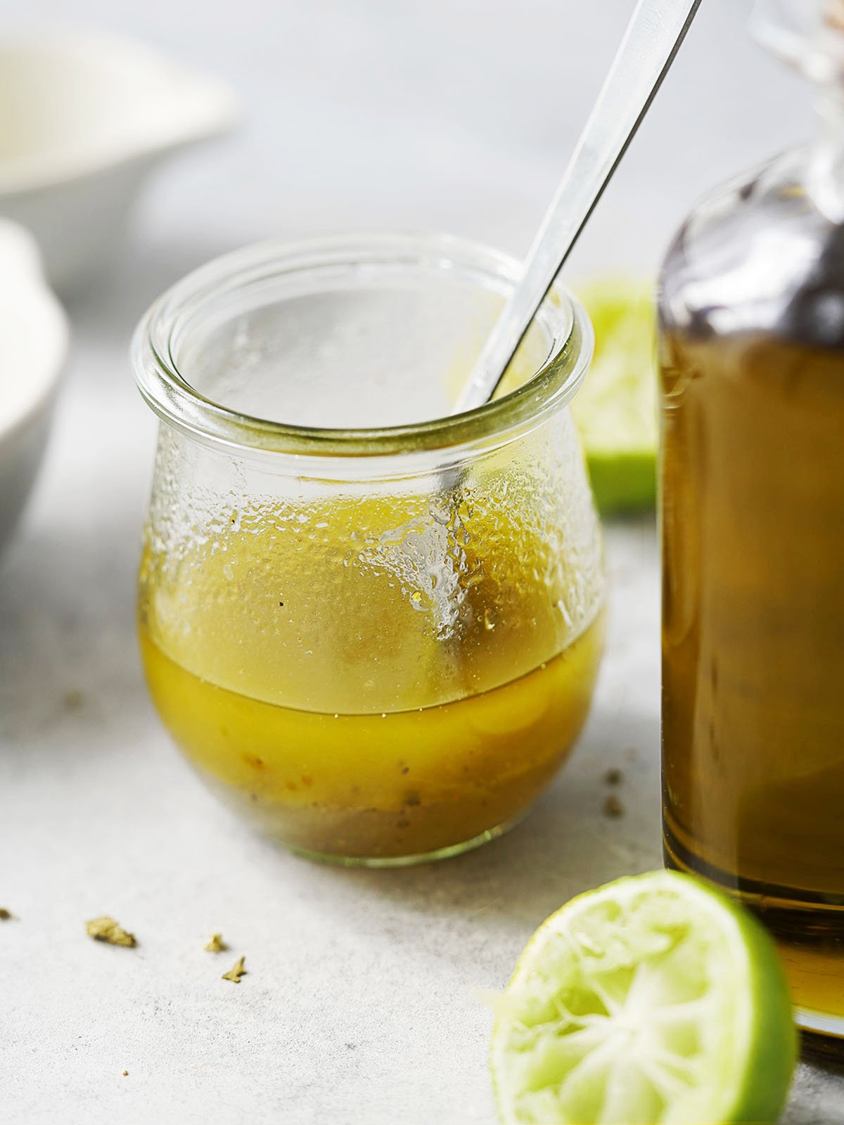 Lime vinaigrette in a small jar with a squeezed lime on the side and olive oil.