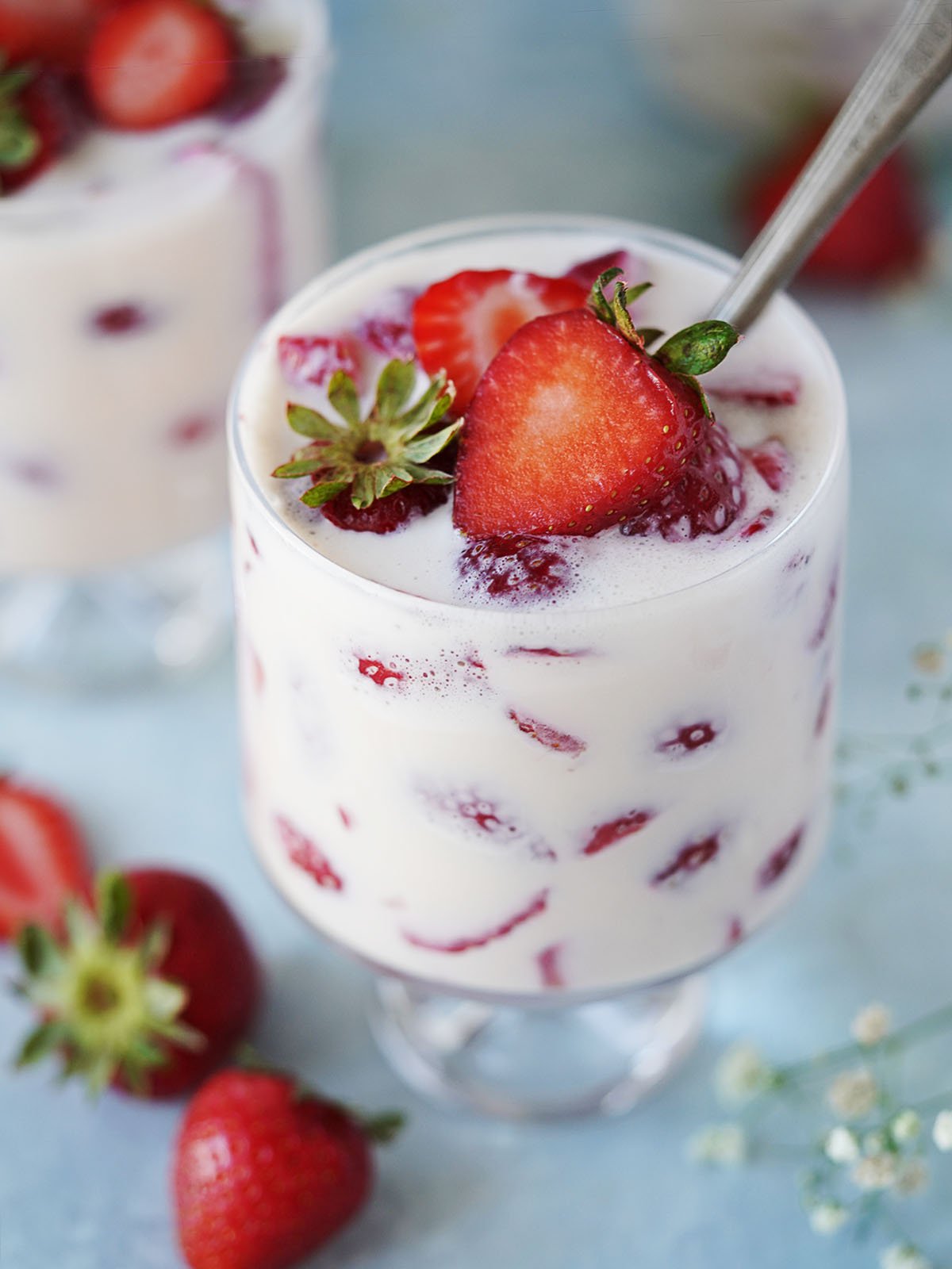 A small glass with fresas con crema topped with a fresh strawberry.