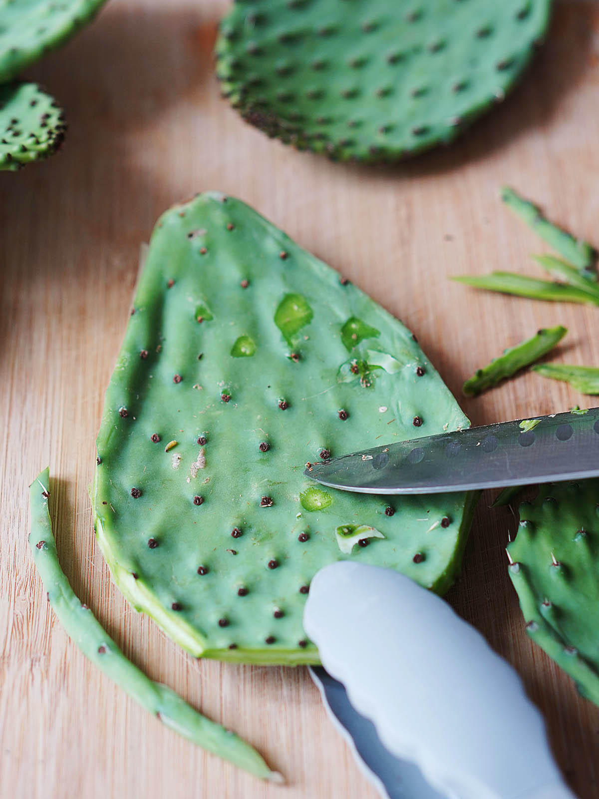 A knife scraping off its thorns of a cactus paddle.