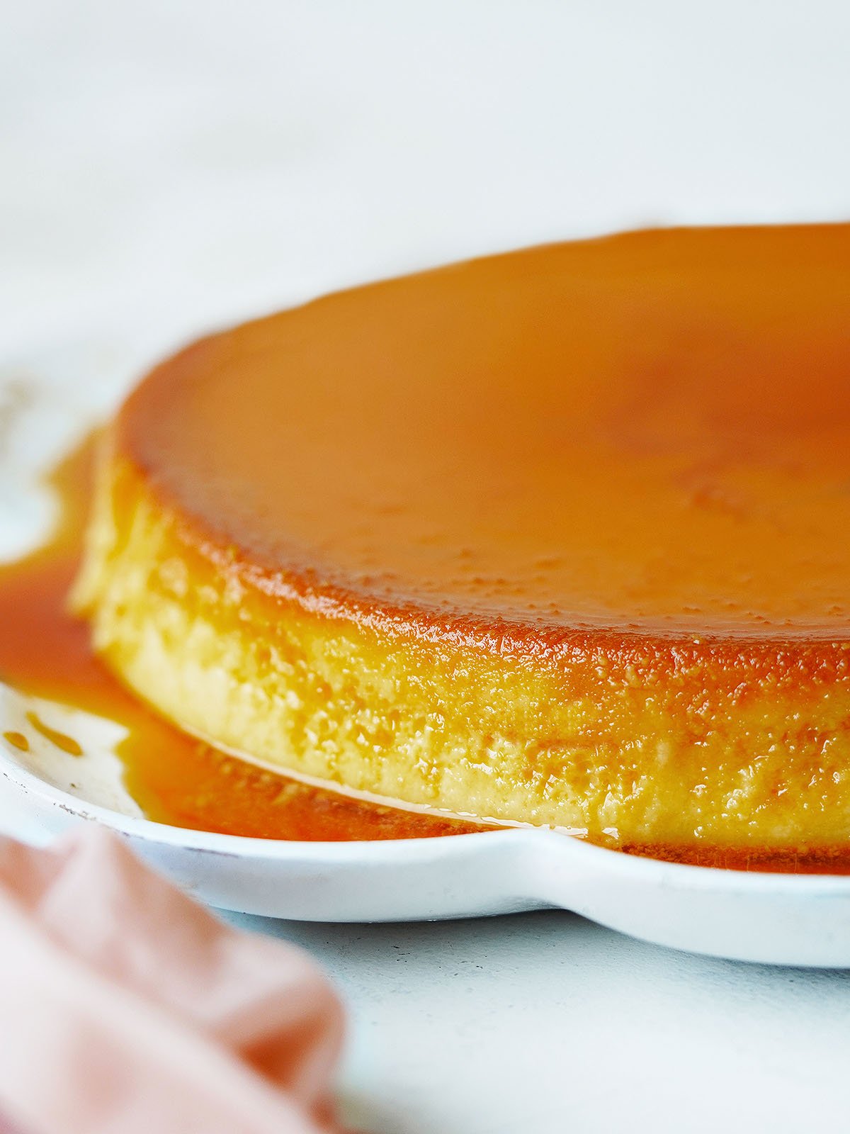 Mexican flan on a white serving plate covered with caramel sauce.