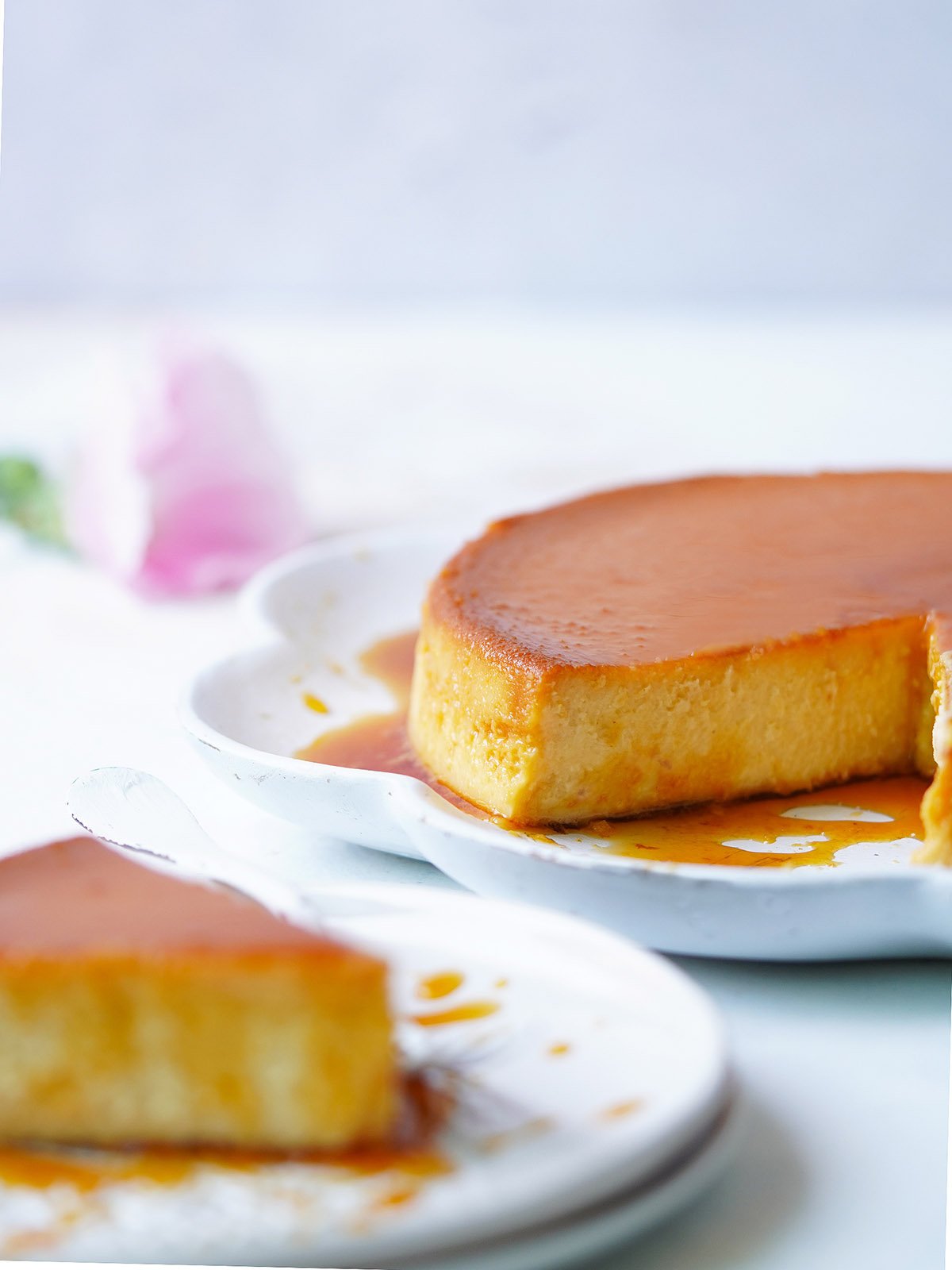 Mexican flan on a white serving plate with a slice on the side.
