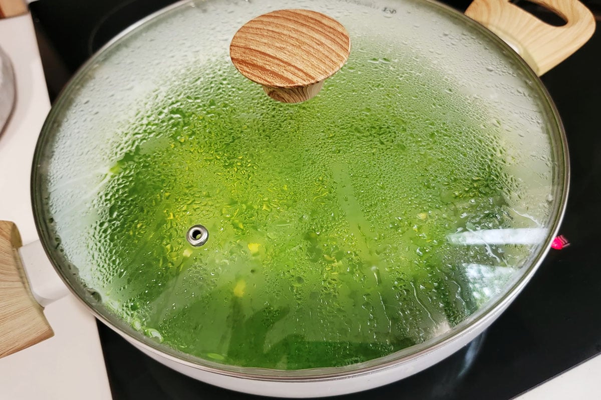 Cooking arroz verde in a white pot and covered with a clear lid.