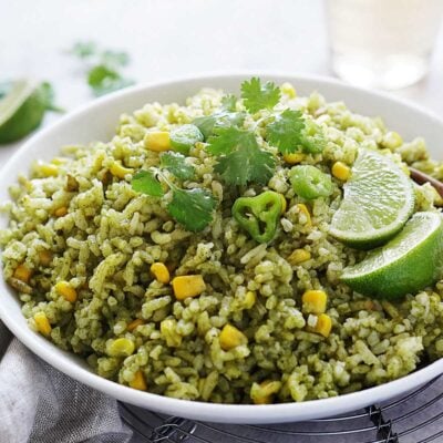 A white bowl with arroz verde garnished with cilantro and sliced peppers.