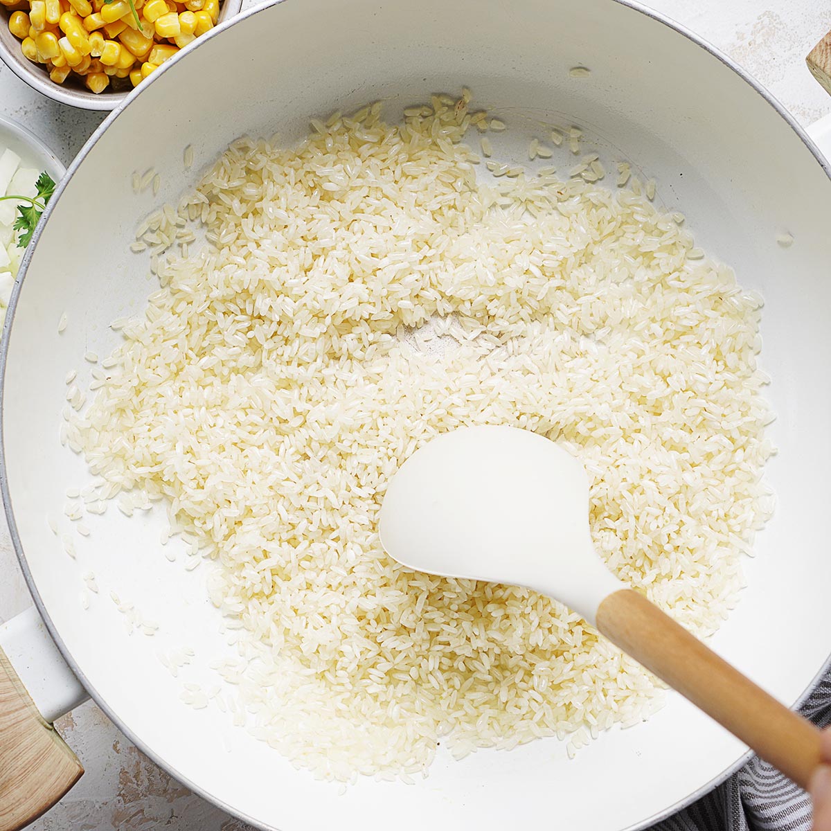 Sauteing white rice in a white pot.