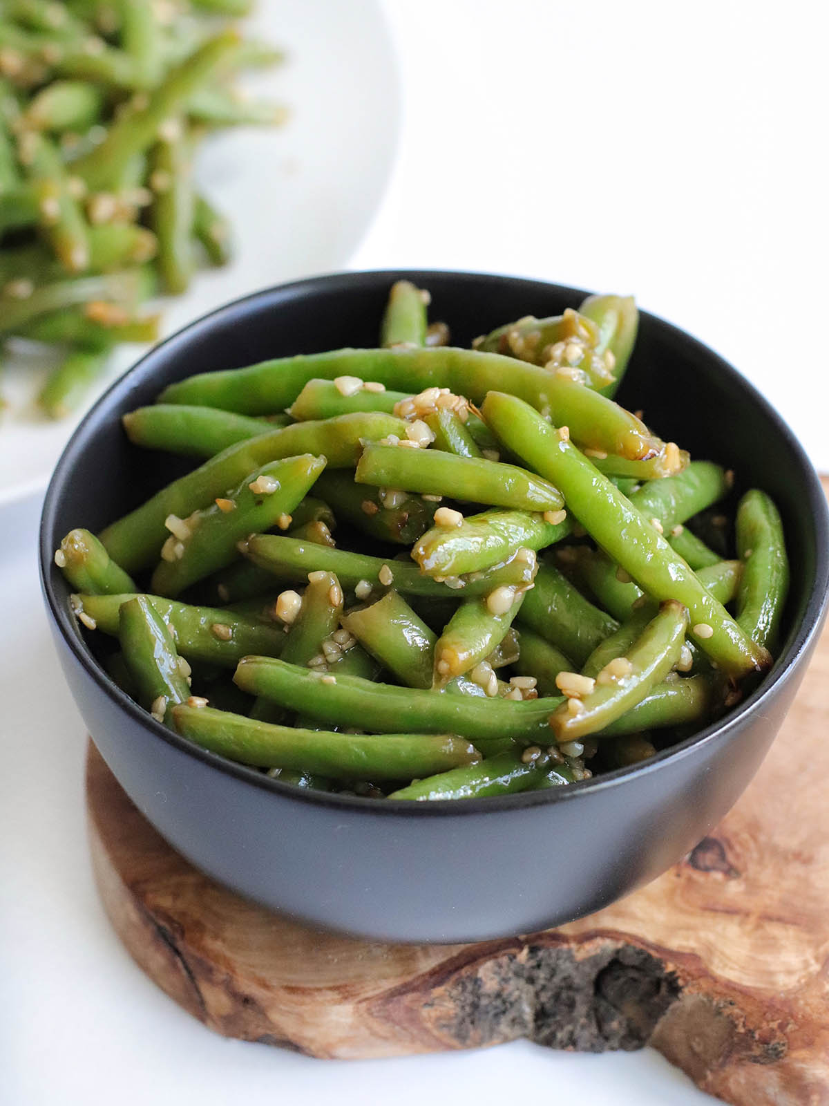 A gray bowl with green beans and lots of garlic.
