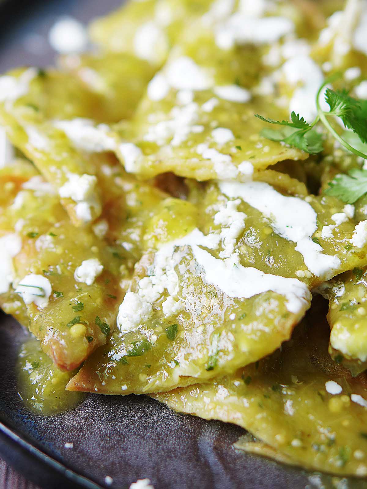 A close up photo of green chilaquiles with Mexican crema.