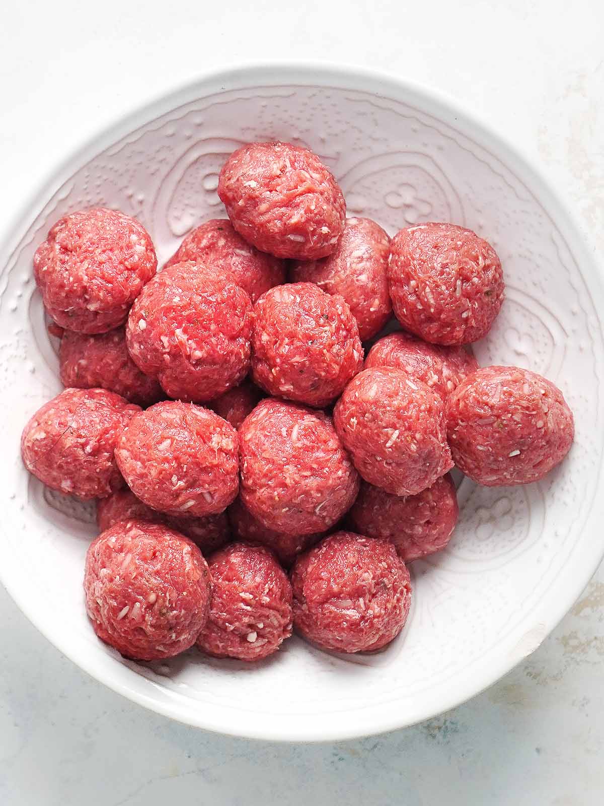 A bowl with raw meatballs.