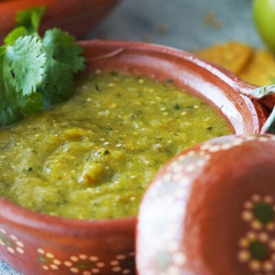 salsa verde placed in a clay bowl with a wooden spoon.