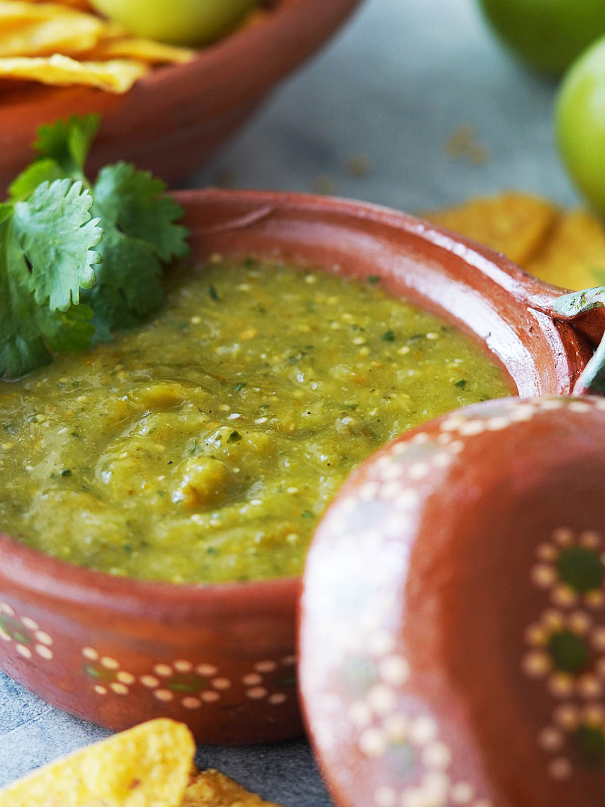 Salsa verde placed in a clay bowl with a wooden spoon.