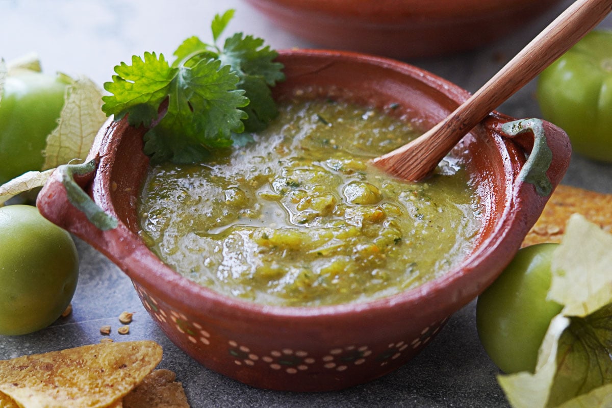 salsa verde placed in a clay bowl with a wooden spoon.