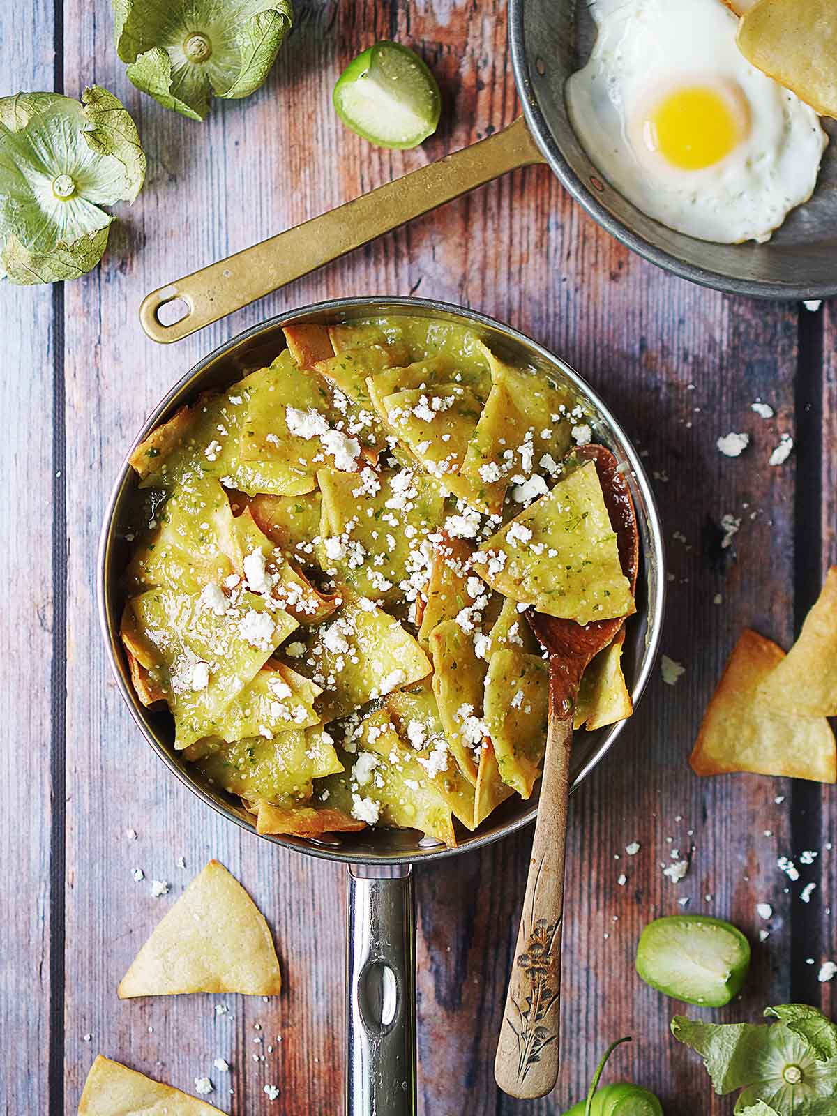 A skillet with fried tortillas smothered in salsa verde.