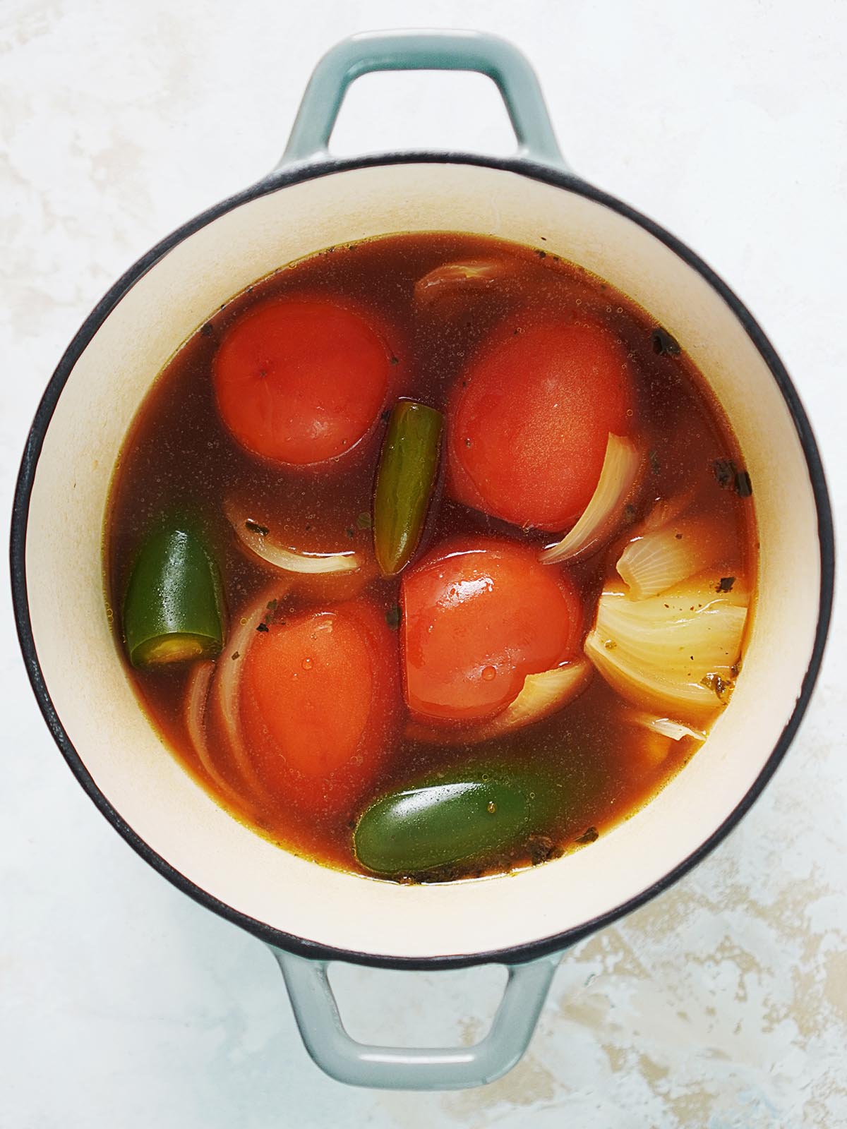 Cooked tomatoes, onions, jalapeños in broth in a medium saucepan.