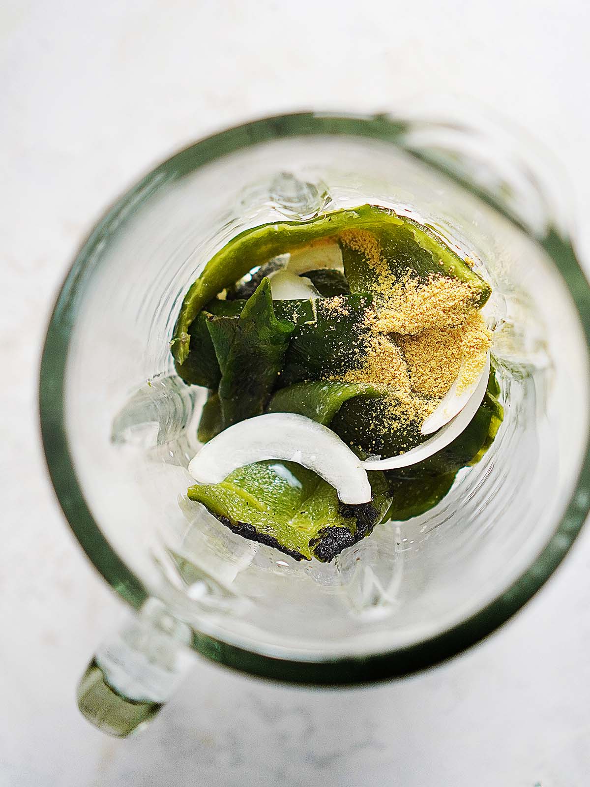A blender's glass with the roasted poblano peppers and onions.
