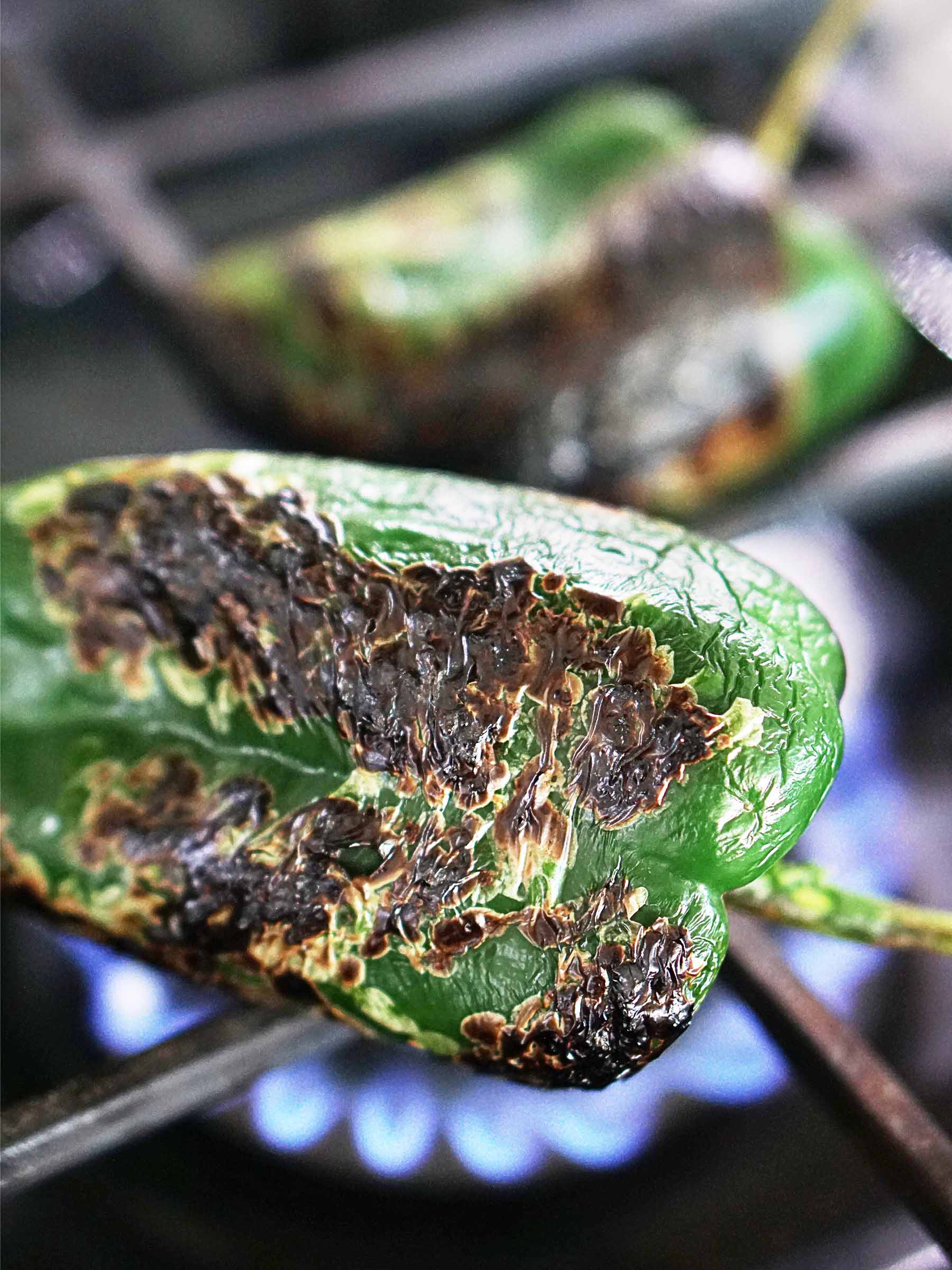 Roasting a poblano pepper on the stove fire.