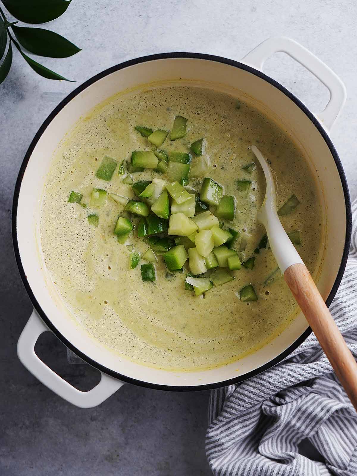 The chunks of chayote were added into the creamed vegetables in the pot.