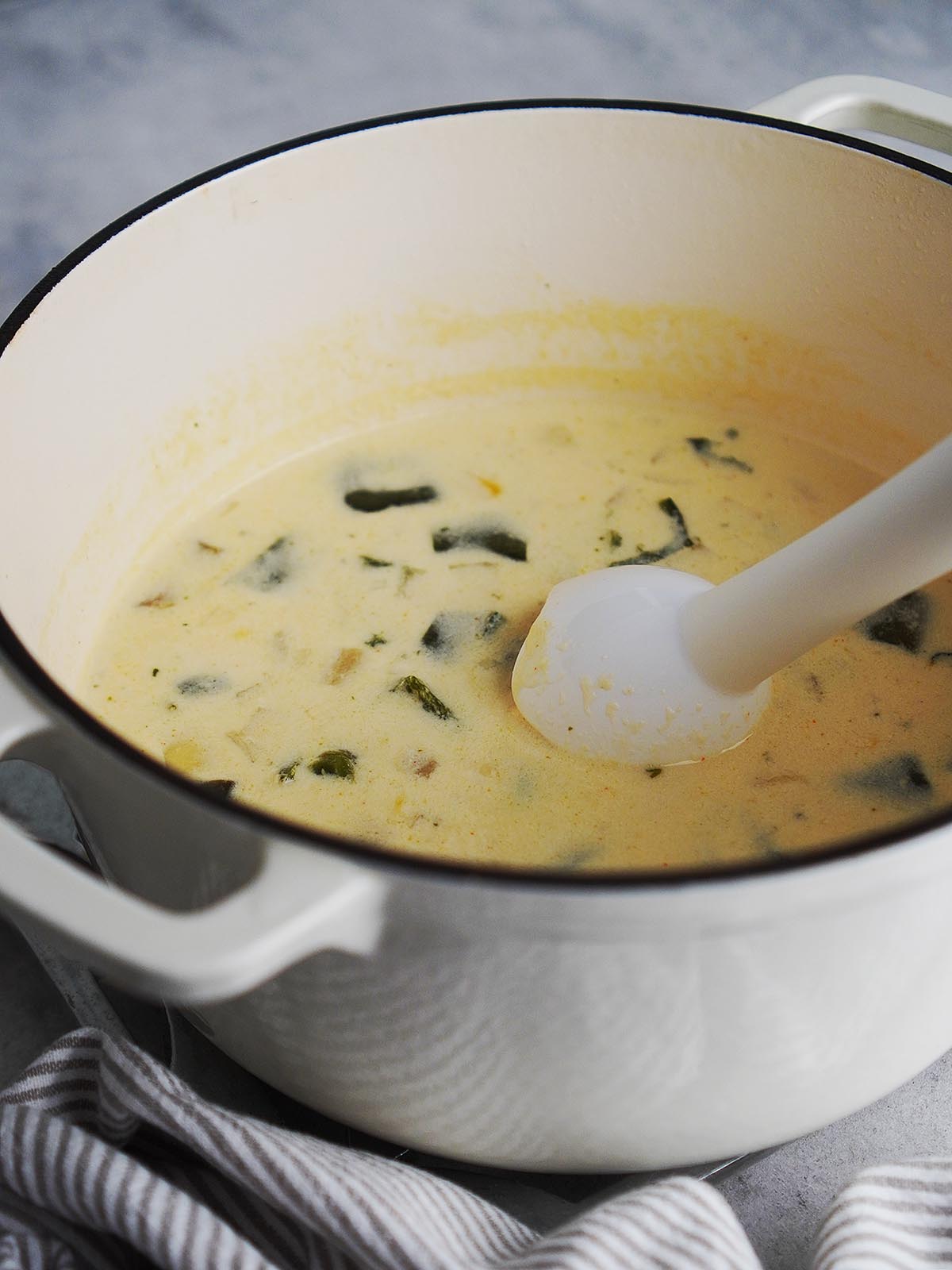 Blending soup with an immersion blender in the pot.